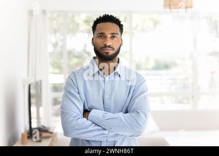Serious African freelance business man in office shirt standing indoors Stock Photo