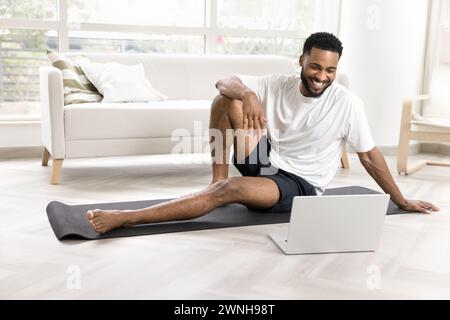Cheerful young African man in sportswear watching fitness video lesson Stock Photo