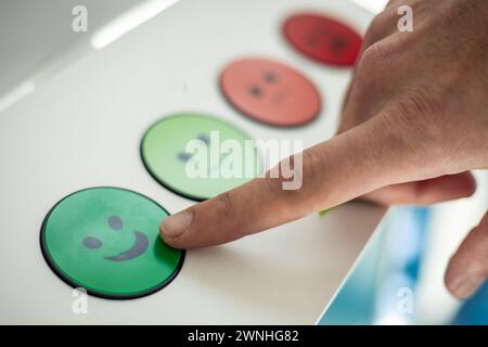 closeup hand pressing green happy face button on a rating panel Stock Photo