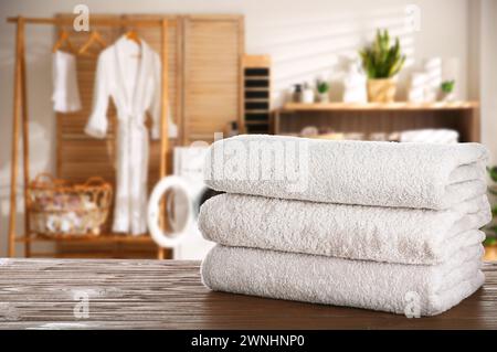 Folded clean towels on wooden table in laundry room, space for text Stock Photo