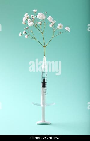 Cosmetology. Medical Syringe And Gypsophila On Light Blue Background 