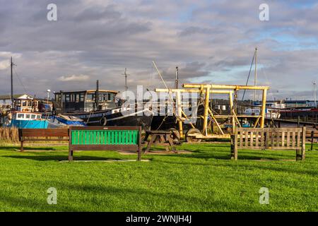 Pin Mill, Suffolk, England, UK - November 22, 2022: Benches at the harbour with a view of the boats Stock Photo