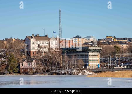 Linnunlaulu villas and centralized traffic control building behind frozen Töölönlahti Bay on a sunny winter day in Helsinki, Finland Stock Photo