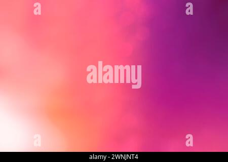 Soft and glowing orange, purple and pink color gradient background with bokeh effect. Abstract bright, vibrant, blurred and multi-colored background. Stock Photo