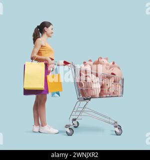 Happy young woman pushing a shopping cart filled with piggy banks, offers and sales concept Stock Photo