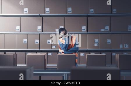Exhausted female warehouse worker sleeping at work, work burnout concept Stock Photo
