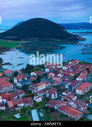 Church of Santa Cruz and town of Escalante seen from a drone in the Parque Natural de las Marismas de Santoña, Victoria y Joyel Natural Park. Cantabri Stock Photo