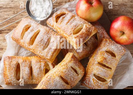 Puff Pastry Apple Turnovers on baking paper close-up on a wooden table. Horizontal top view from above Stock Photo