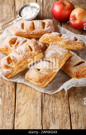 Freshly baked puff pastry with apples on baking paper close-up on a wooden table. Vertical Stock Photo