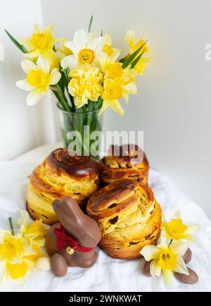 This vibrant image captures a delightful scene of Easter treats and spring vibes. Freshly baked pastries, a chocolate bunny, and colorful daffodils cr Stock Photo