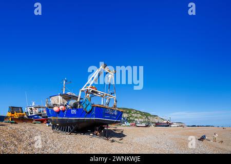Beached traditional small fishing boats hauled up on the shingle beach at Hastings, East Sussex, south coast England Stock Photo