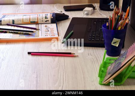 The picture shows a mess left on the table in the office, pencils, a laptop, a magazine. Stock Photo