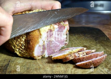 Close-up of a pork leg being cut with a knife. Close-up shot. Stock Photo