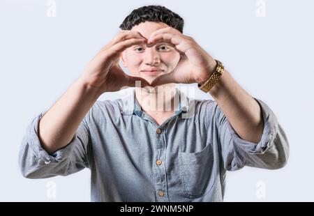 Handsome young man making heart shape with hands isolated. Smiling latin man making heart shape with hands Stock Photo