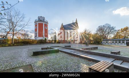 The sun shines through trees next to a historic red observation tower and brick house, Elisenturm, Villa Eller, Botanical Garden, Hardt, Elberfeld Stock Photo