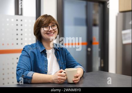 Young woman on a coffee break in the office kitchen Stock Photo