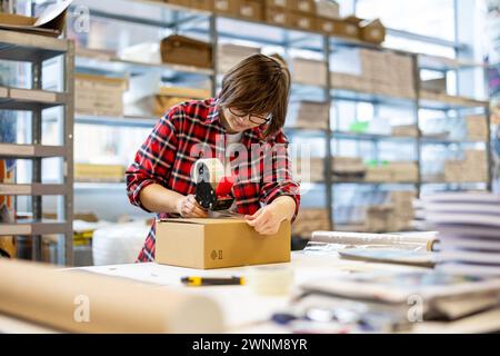 Female Worker Taping Cardboard Box Stock Photo