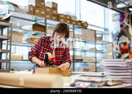 Female Worker Taping Cardboard Box Stock Photo