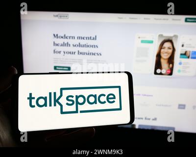 Person holding smartphone with logo of US online psychotherapy company Talkspace Inc. in front of website. Focus on phone display. Stock Photo