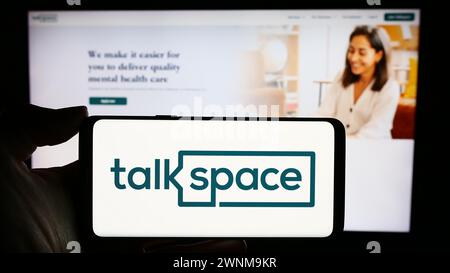 Person holding cellphone with logo of US online psychotherapy company Talkspace Inc. in front of business webpage. Focus on phone display. Stock Photo