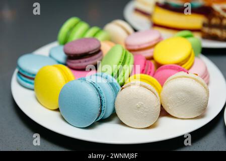 A vibrant selection of French macarons displayed on a white plate, perfect for dessert or afternoon tea. Stock Photo
