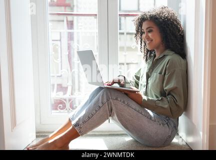 Smiling black woman works and studies on laptop from home Stock Photo