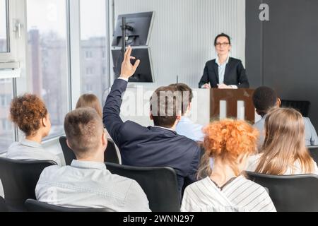 Businessman raising hand at seminar, having question to speaker Stock Photo