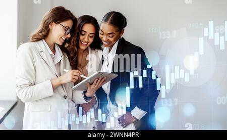 Three professional women engaging in a collaborative discussion over a tablet Stock Photo