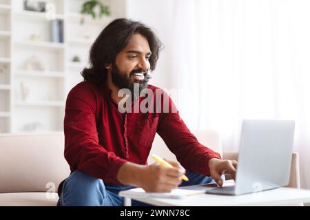 Positive young indian man studying from home Stock Photo