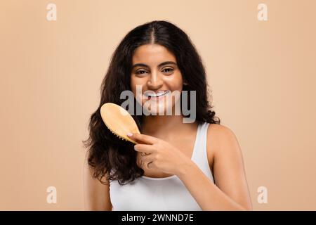 Cheerful young indian woman brushing her thick, wavy hair Stock Photo