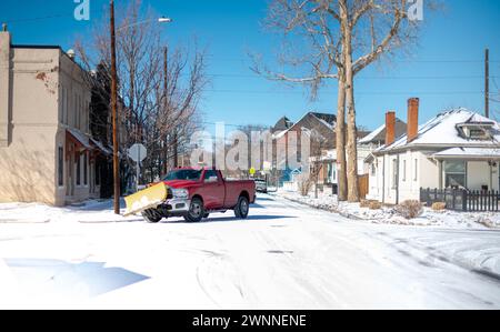 The red snowplow truck cleared fresh snow from street in a residential area in the Downtown city of Denver, Colorado. Stock Photo