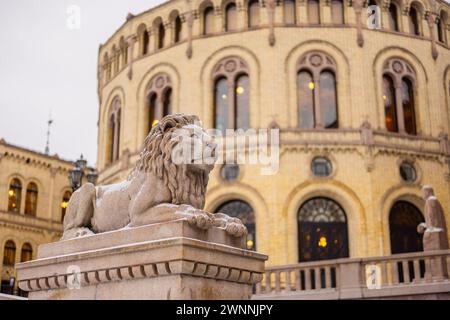 Statue of a lion in front of the house of norwegian parliament on a cold winter day. Lion peacefully resting on a pillar in front of majestic building Stock Photo