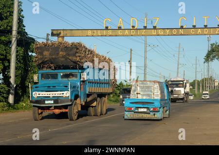 Overloaded trucks carrying sugarcane crop on road from Cadiz City to Bacolod, Negros Occidental, Philippines. Stock Photo