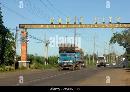 Overloaded trucks carrying sugarcane crop on road from Cadiz City to Bacolod, Negros Occidental, Philippines. Stock Photo