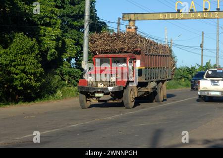 Overloaded trucks carrying sugarcane crop on road from Cadiz City to Bacolod, Negros Occidental, Philippines. Stock Photo