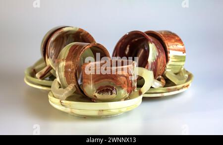 Empty cups made of multi-colored onyx in yellow-orange tones on a white background. Stock Photo
