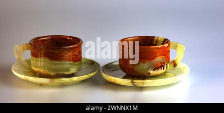Empty cups made of multi-colored onyx in yellow-orange tones on a white background. Stock Photo
