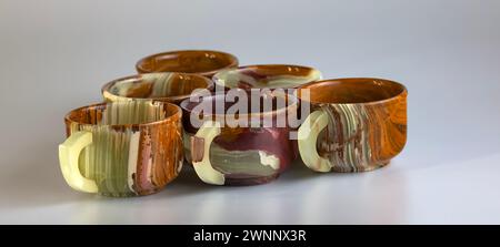 Empty cups made of multi-colored onyx in yellow-orange tones on a white background. Stock Photo