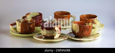Empty cups made of multi-colored onyx in yellow-orange tones on a white background. Stock Photo