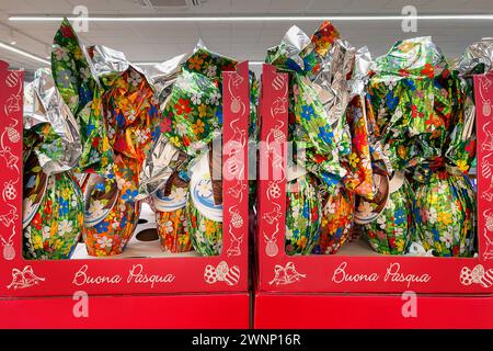 Easter eggs wrapped in colorful paper decorated with flower designs displayed in red boxes with inscription Buona Pasqua (Happy Easter) for sale in su Stock Photo