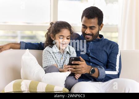 Happy Indian daughter and handsome dad watching funny online content Stock Photo