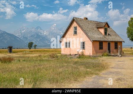 Peaks of the Grand Tetons rise up behind The Pink House on Mormon Row in the Historic District of the Grand Teton National Park in Wyoming Stock Photo