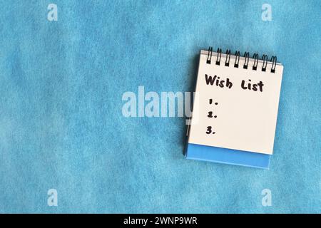 Wish list concept. White note pad isolated on blue background. Stock Photo