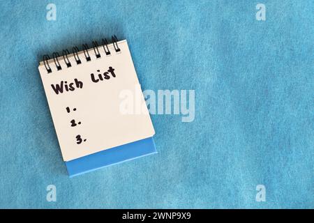 Wish list concept. White note pad isolated on blue background. Stock Photo