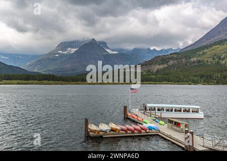 Chief Two Guns tour boat approaching the floating dock on Swiftcurrent Lake at Many Glacier Hotel in Glacier National Park, Montana Stock Photo