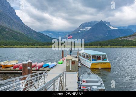 Chief Two Guns tour boat approaching the floating dock on Swiftcurrent Lake at Many Glacier Hotel in Glacier National Park, Montana Stock Photo