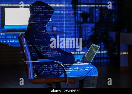 Hacker using laptop and projection of programming code in dark room Stock Photo