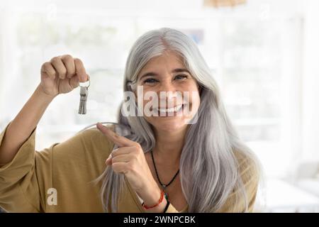 Happy retired elderly Latin woman showing keys from new home Stock Photo