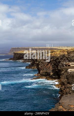 View of the cliffs at South Point or Ka Lae, Big Island, Hawaii, the southernmost point in the USA, with the Pakini Nui Wind Farm in the distance. Stock Photo