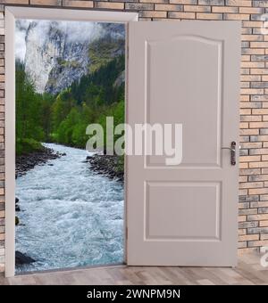 Open door in brick wall inviting to visit mountains Stock Photo